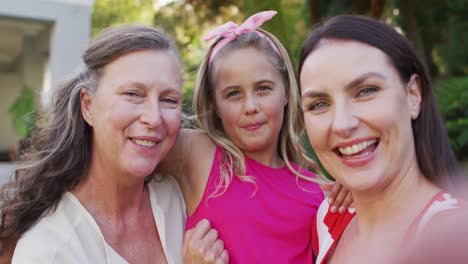 retrato de una abuela, una nieta y una madre caucásicas felices abrazándose en el jardín y sonriendo