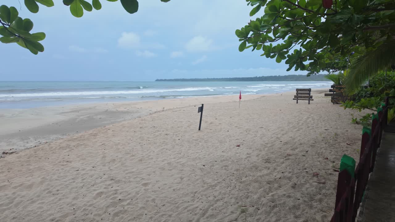 A tranquil beach scene in Cahuita, Costa Rica, featuring sandy shores, lush greenery, and the Caribbean Sea under an overcast sky