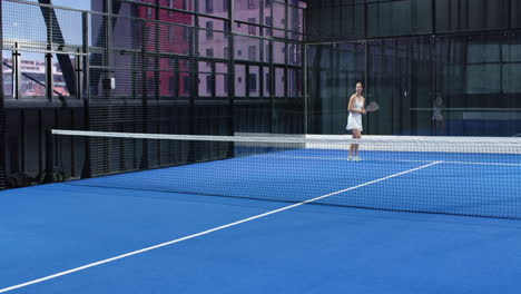 women playing padel tennis on blue indoor court, enjoying competitive match
