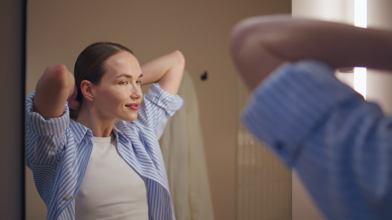 Happy girl making ponytail in mirror reflection. Daily morning routine at home