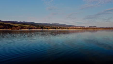 Niedrige-Überführung,-Ruhiges-Wasser-Eines-Blauen-Sees-Mit-Himmelsreflexion