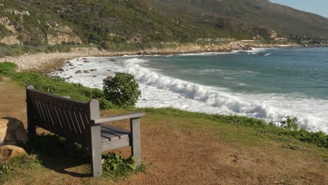 Banco-Con-Vistas-A-Las-Olas-Rompiendo-En-Una-Pequeña-Playa-Rocosa-En-Ciudad-Del-Cabo