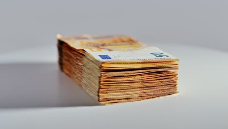 stack of fifty euro bills rotating slowly on smooth white table under lighting