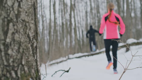 Positives-Schönes-Junges-Gesundes-Paar,-Das-Am-Sonnigen-Wintermorgen-Mit-Sportkleidung-Durch-Den-Wald-Läuft.-Springe-über-Den-Baum-Und-überwinde-Die-Schwierigkeiten-Des-Weges.-über-Ein-Hindernis-Steigen