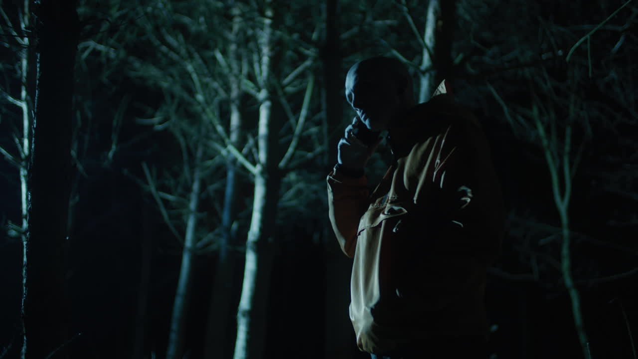 Man using phone in a snowy forest at night