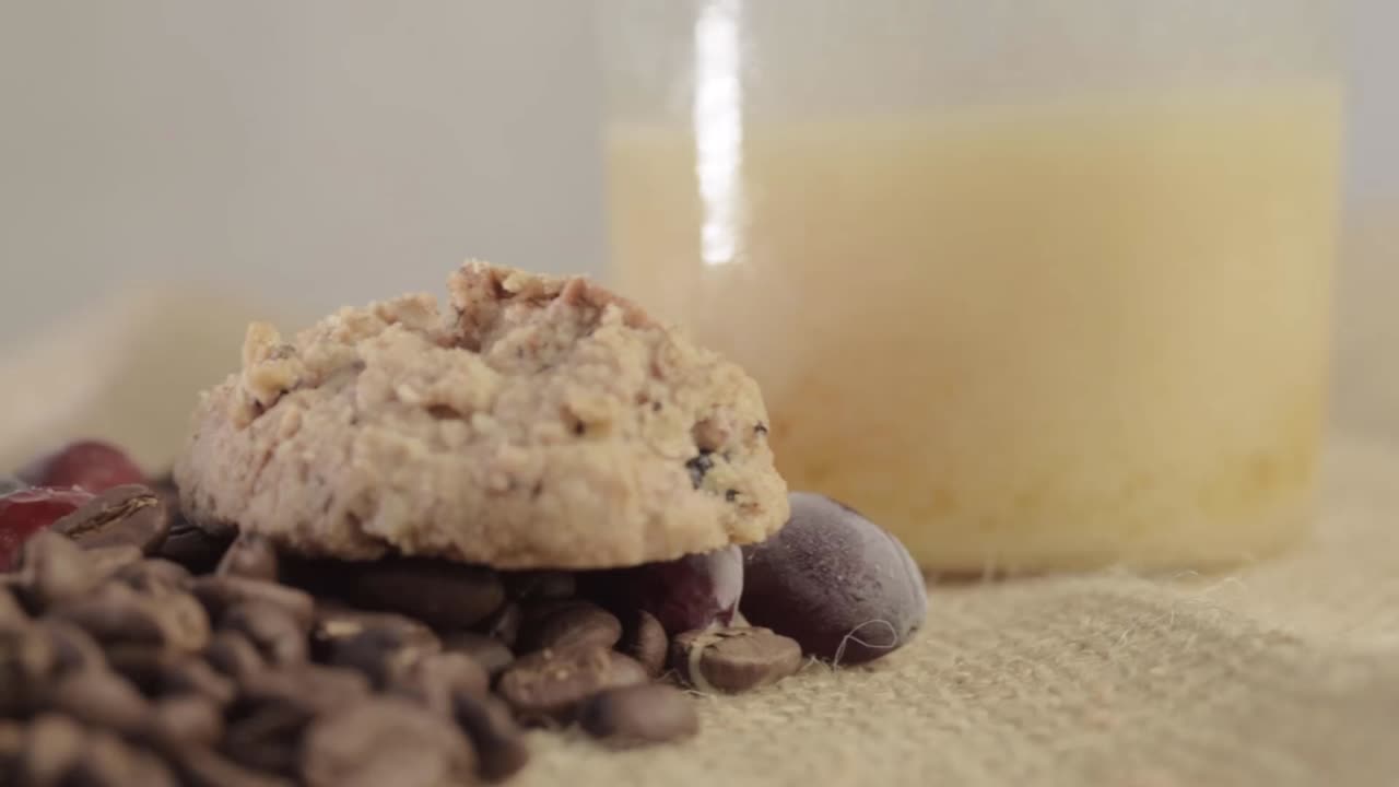 Fresh roasted coffee beans and cookies on hessian background medium panning shot