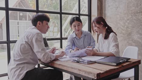 젊은 아시아인들은 성공적인 프로젝트를 위해 서로 박수를 치며, 창의적인 사무실에서 일하면서 똑똑한 캐주얼 옷을 입고 웃고 있습니다.