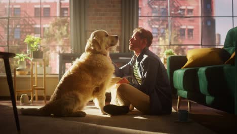 young adult man having fun, training with his golden retriever pet on a living room floor. dog owner offering a snack in exchange for shaking dog's paw.