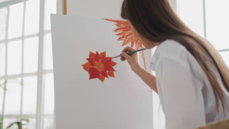 artista femenina dibuja una flor roja en el lienzo cerca de la ventana