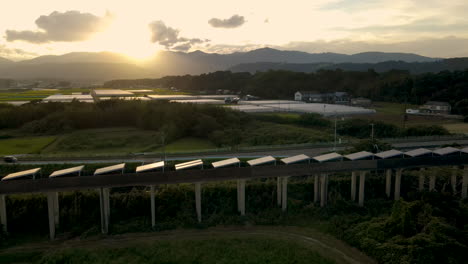 Panning-Aerial-Of-Solar-Panels-On-An-Abandoned-Monorail-Track-In-Japan-At-Sunset