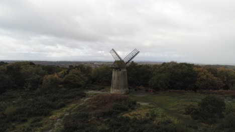 Traditional-wooden-stone-flour-mill-windmill-preserved-in-Autumn-woodland-aerial-view-countryside-rear-view