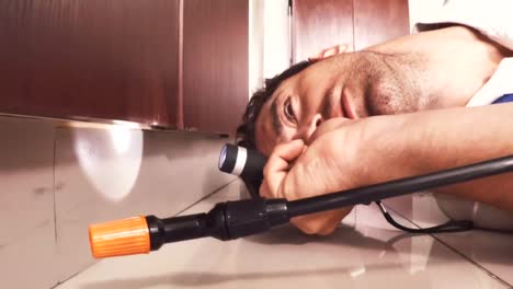 pest control man spraying pesticide under the cabinet