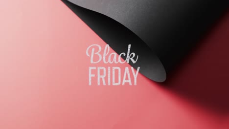 Animation-of-black-friday-text-over-rolled-up-black-paper-on-red-background
