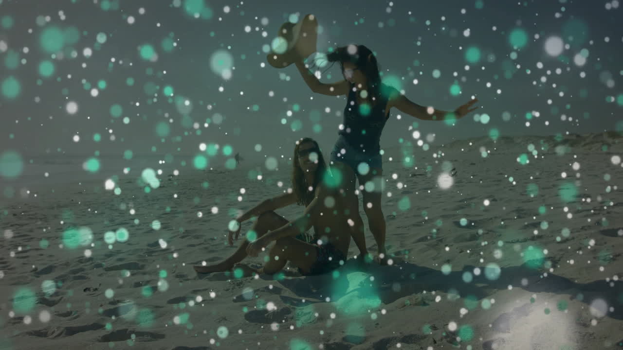 friends sitting on beach adjusting straw hat, showing marketing concept with floating bokeh lights