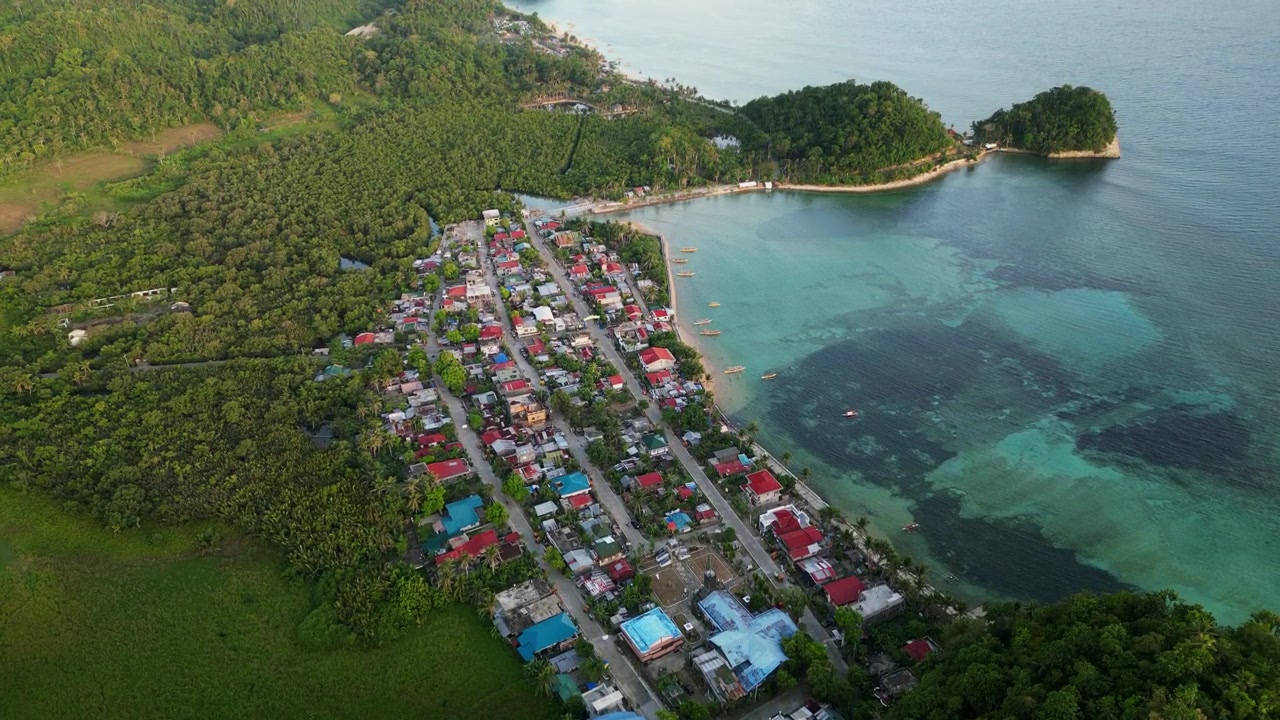 Vista aerea ascendente di un rigoglioso villaggio di pescatori lungo la costa tropicale di Catanduanes, Bicol, Filippine