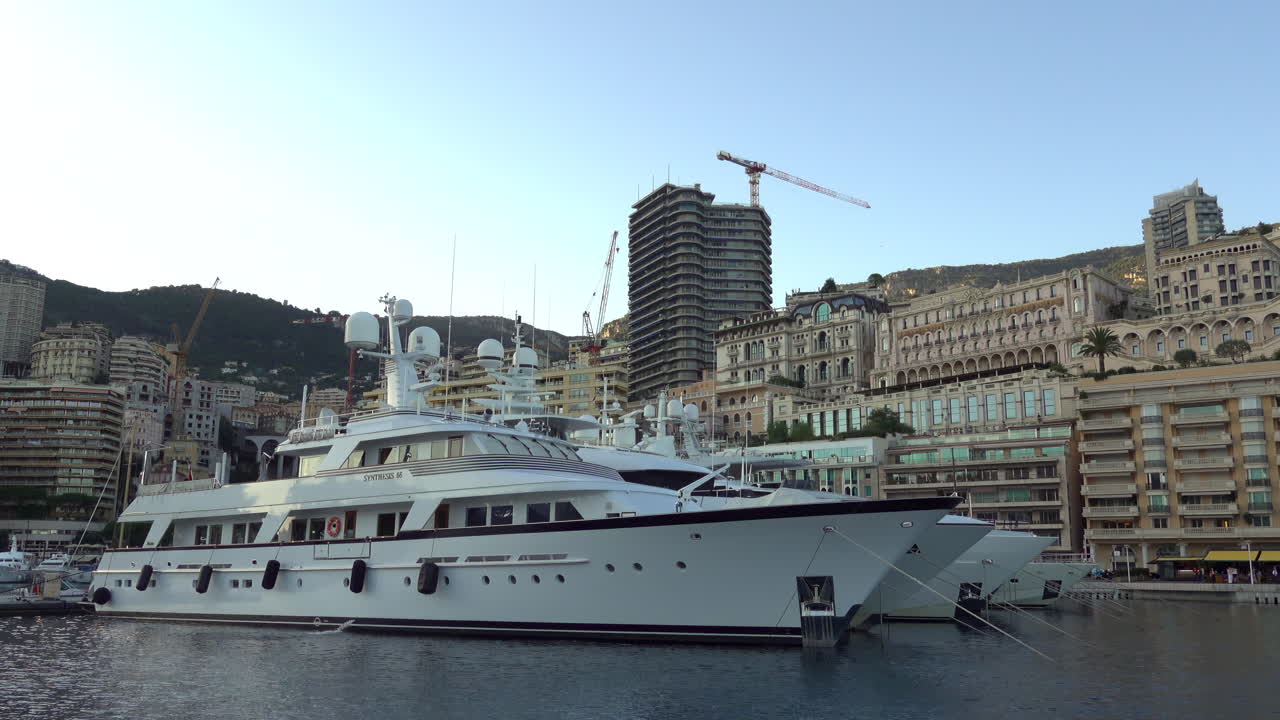 Monte Carlo, Monaco - July 4, 2025: Yachts and launches tied up near the modern tiered Yacht Club building, with luxury residences along the quay