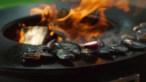 unknown man grilling mussels outside. male chef preparing seafood on mangal