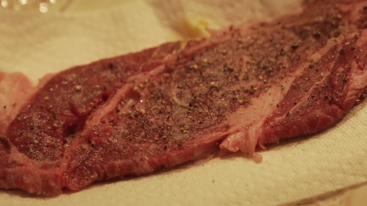 Slow Motion Panning shot of raw wagyu beef steak being seasoned and prepped for cooking. HD 1080p 23.98p