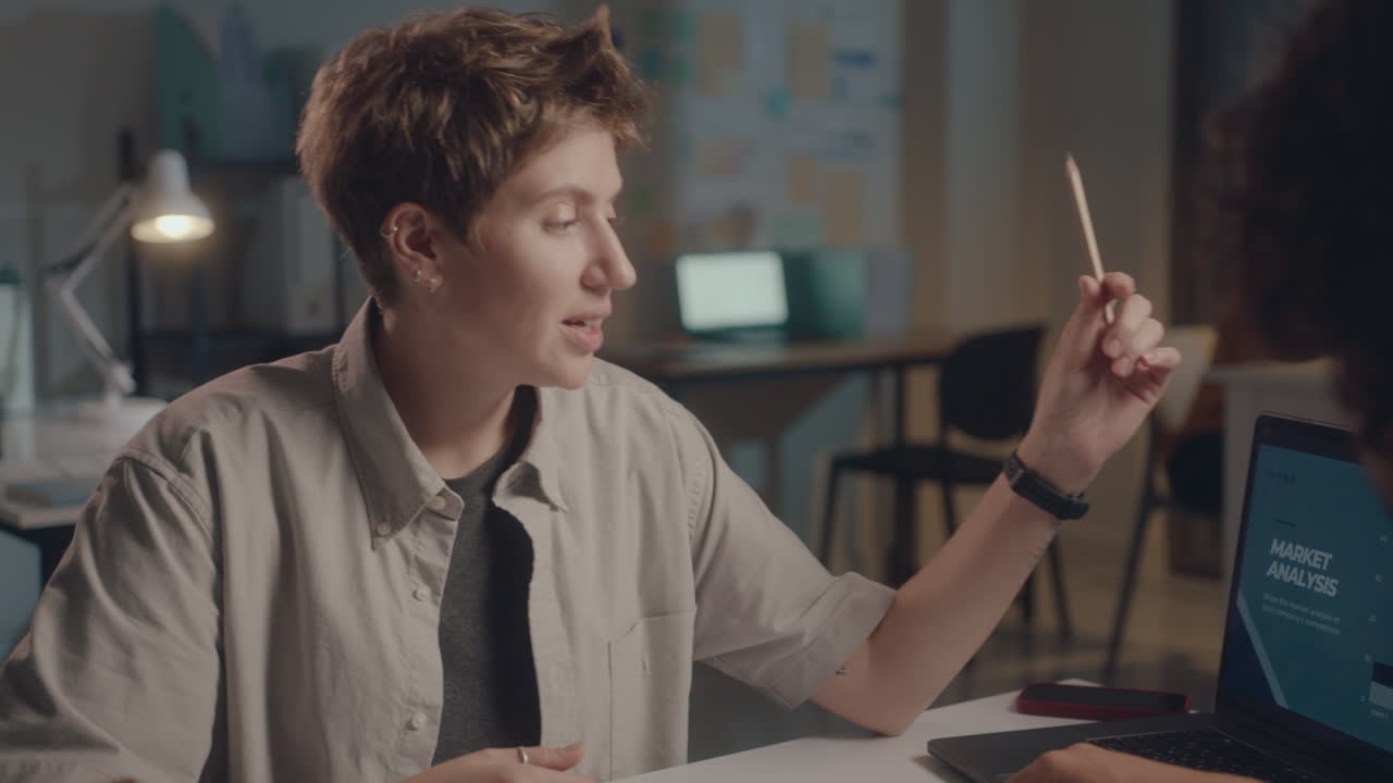 Coworkers Discussing Business Presentation on Laptop at Night