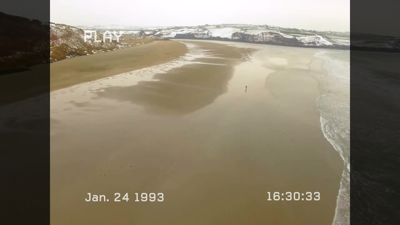VHS AFSPILNING starter 16:30:22, droneoptagelse af vandrer på sand med glitch-linjer for vintage-optagelser.