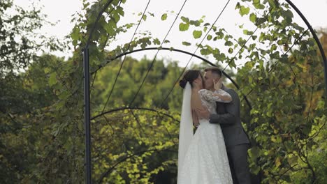 lovely newlyweds caucasian bride embracing groom in park making kiss, wedding couple family hugging