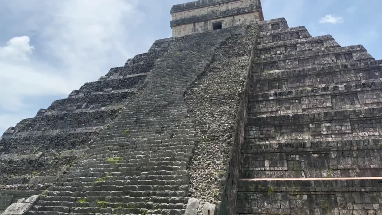 Handheld close-up tilting up shot of the ruins of the steep steps on the backside of Kukulkan's pyramid in Chichen Itza, Mexico. 4K
