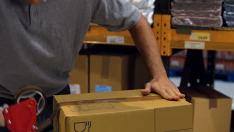 worker sealing cardboard box with packing tape