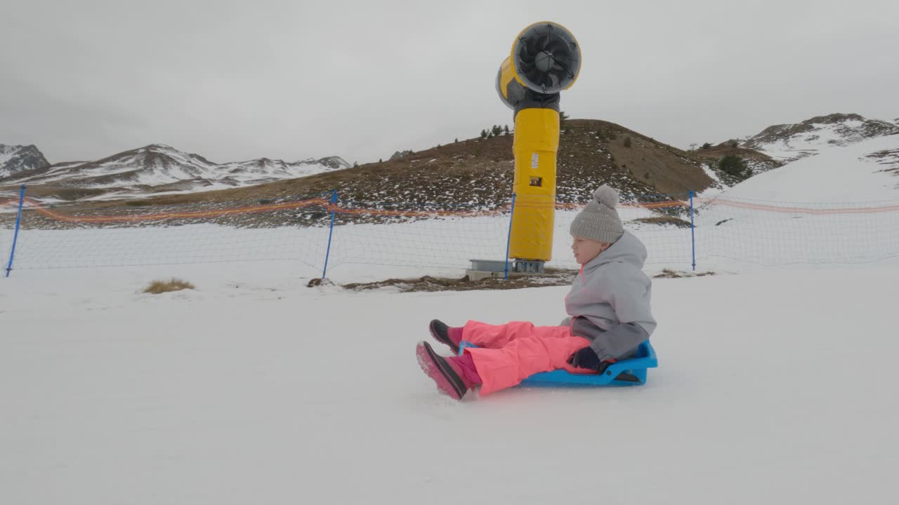 niño en trineo en montañas nevadas