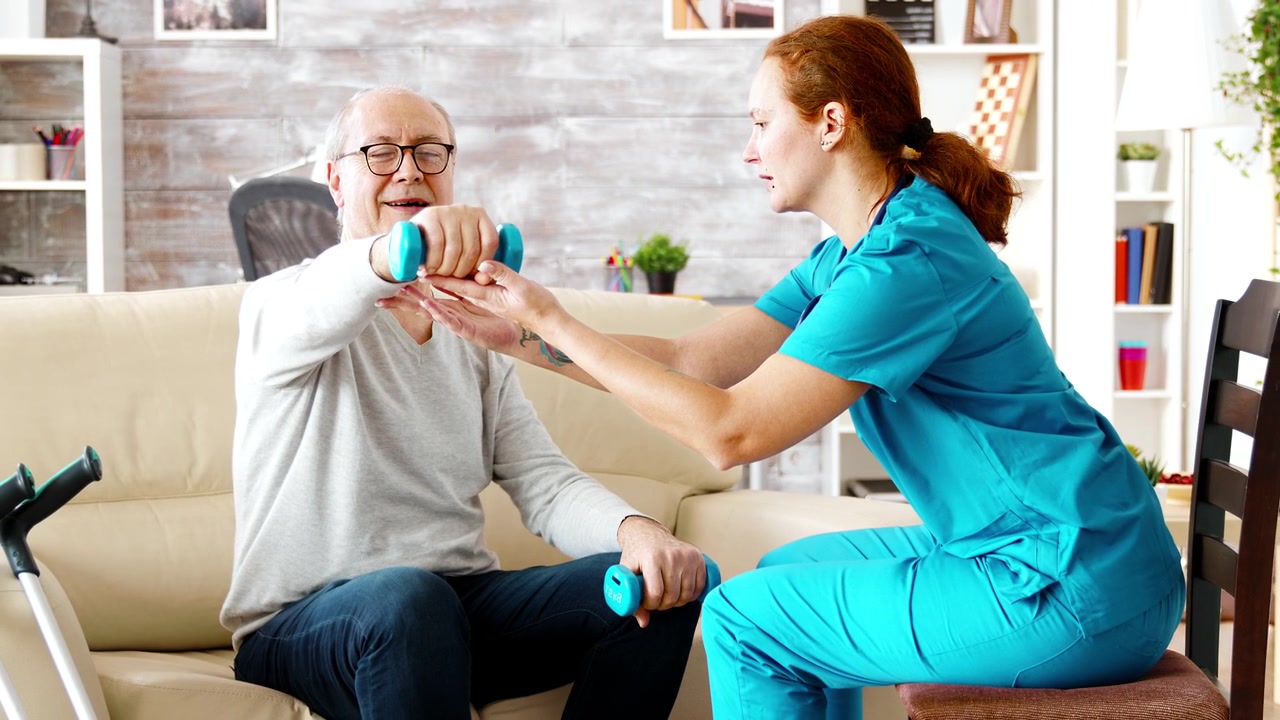 Physiotherapeut unterstützt Senior bei Hantelübungen