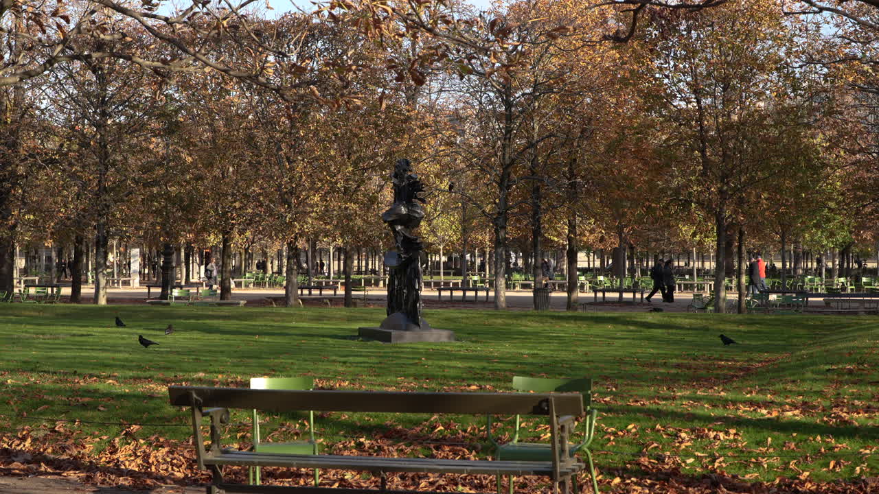 Autumn view of Jardin des Tuileries near the Louvre in Paris, with golden trees, green chairs, and sunlight casting soft shadows across the park