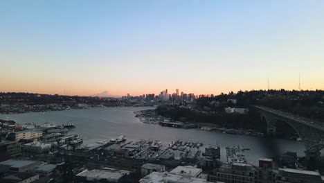 Filmische-Drohnenaufnahme-Des-Lake-Union-Mit-Pier-Und-Parkenden-Booten-Und-Der-Skyline-Von-Seattle-Im-Hintergrund-Zur-Goldenen-Stunde-–-Totalaufnahme