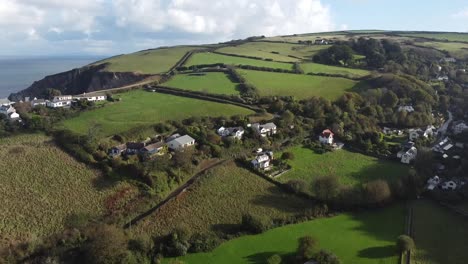 Toma-Aérea-De-Seguimiento-De-Drones-De-Una-Camioneta-Blanca-Que-Viaja-A-Través-De-Un-Pueblo-Inglés-En-El-Campo-Con-Una-Costa-Rocosa---Lee-Bay,-Playa,-Ilfracombe,-Devon,-Inglaterra