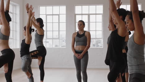 beautiful yoga woman instructor teaching lord of the dance pose meditation with group of multiracial women enjoying healthy lifestyle exercising in fitness studio