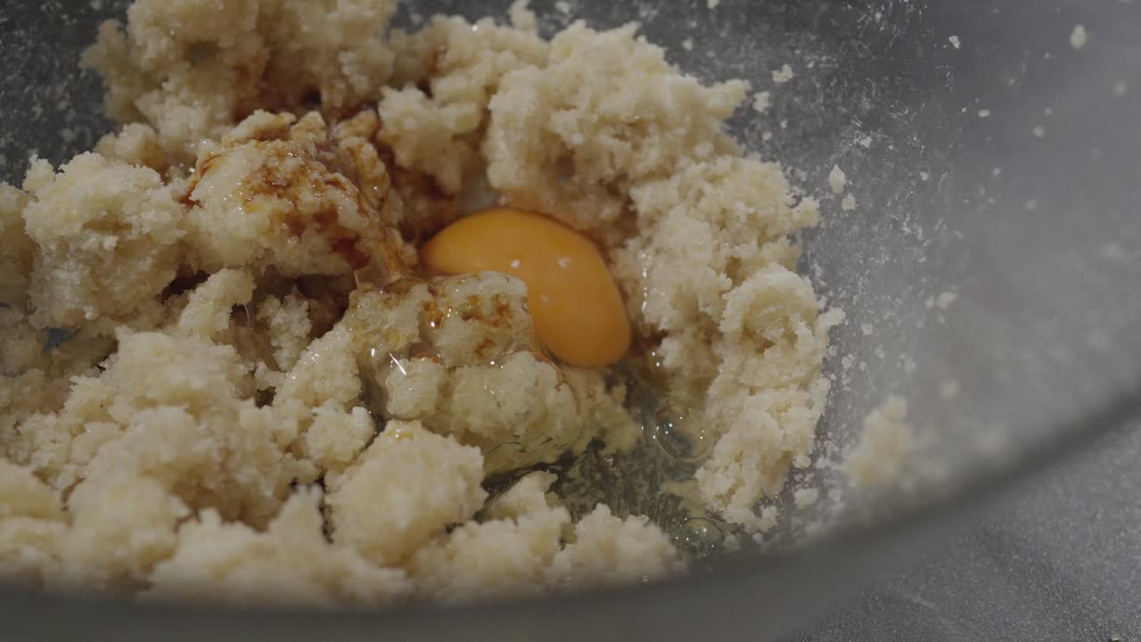 Muna lisätään pikkuleipätaikinaan, samalla kun käsimikseri sekoittaa aineksia kulhossa.