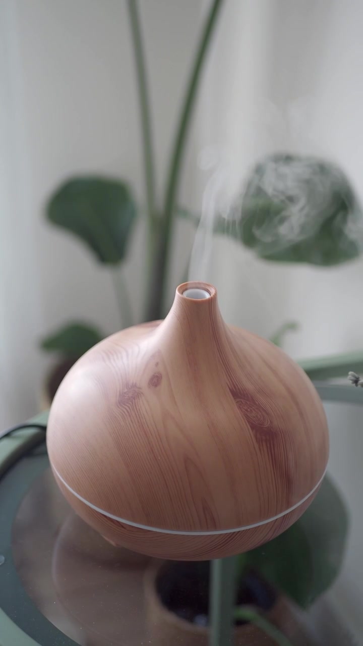 Diffuseur d'huiles essentielles effet bois diffusant de la brume dans un intérieur de maison
