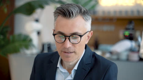 attractive business man with glasses looks directly into the camera and smiles