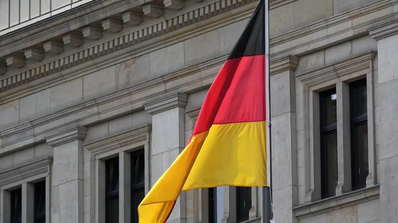 4K. Flag of Germany waving in the wind in front of a historical building