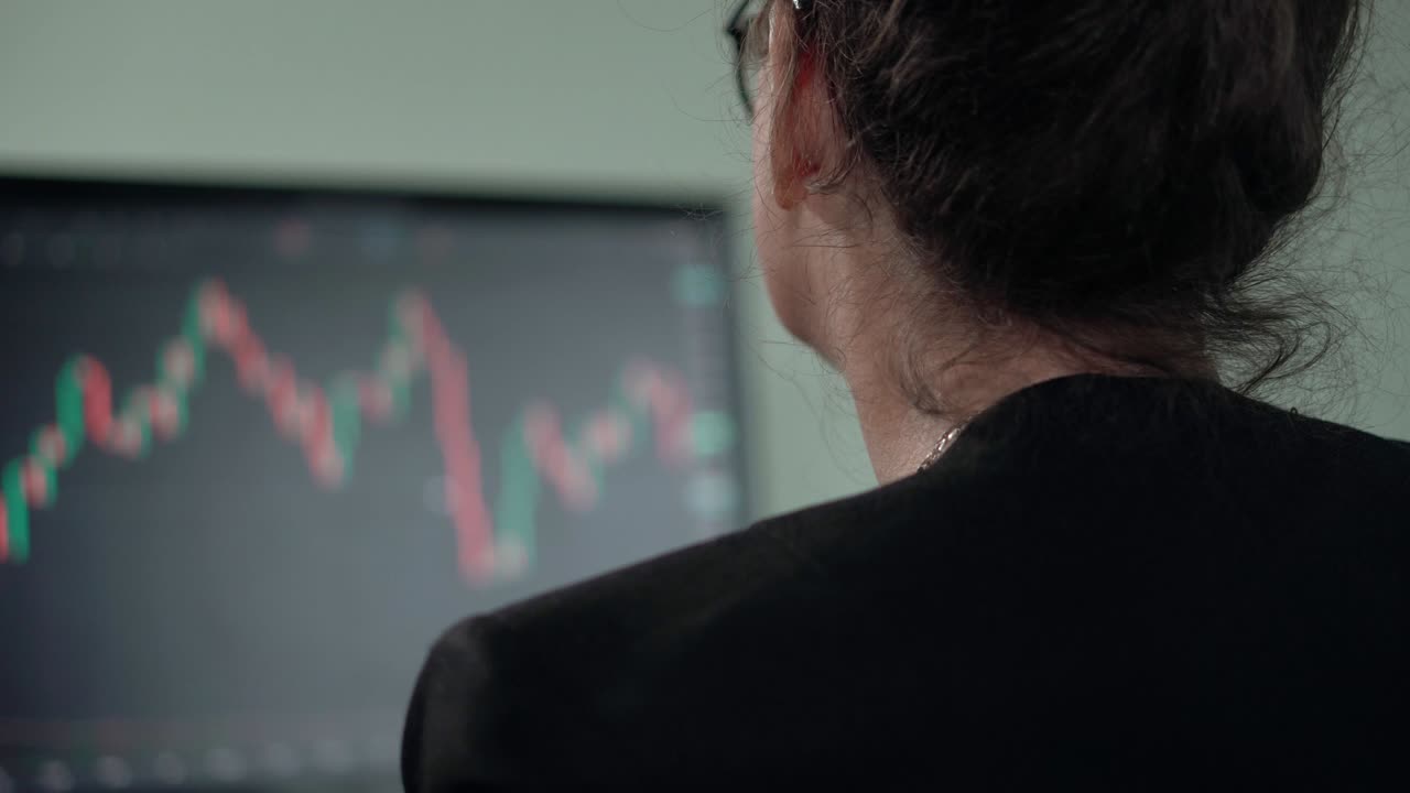 Mature woman brunette looks on monitor searching currency trend