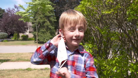 happy little boy taking off his face mask