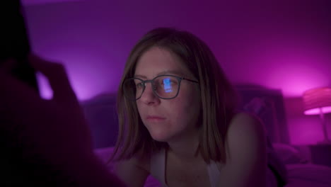 girl browses social media on smart phone late at night in bedroom.
