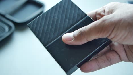 person holding a black external hard drive