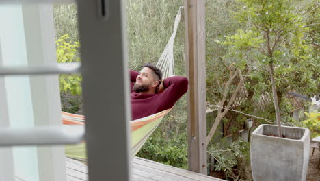 relaxing in hammock, man enjoying peaceful time outdoors on wooden deck