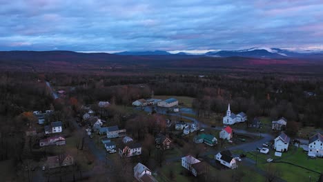 aerial footage flying over small rural community in late fall at sunrise with misty mountains in the distance