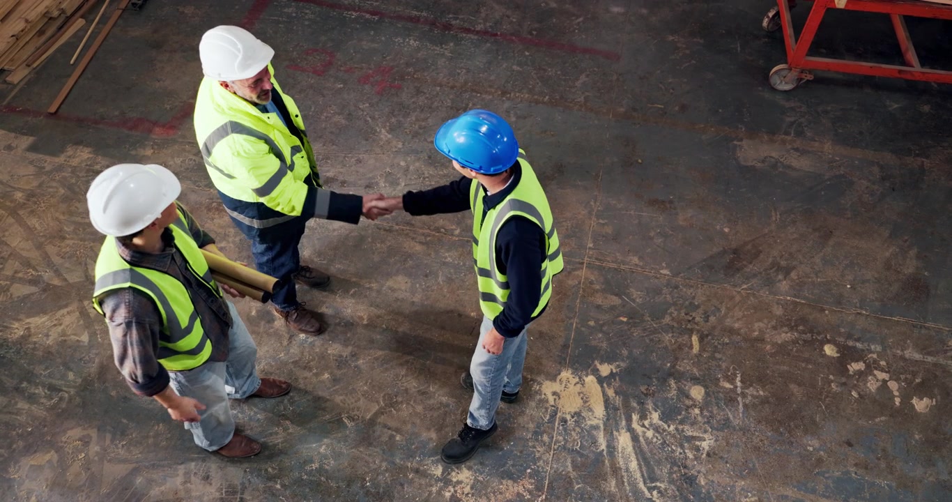 Construction Workers Shaking Hands in Warehouse