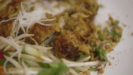 close-up of a dish with fried spring rolls, rice noodles, and fresh vegetables
