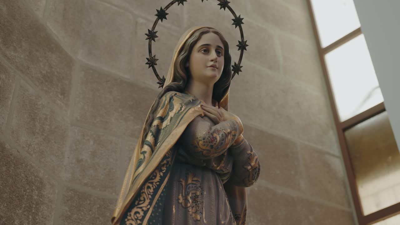 Close-up of Virgin Mary statue with star halo and folded hands inside church