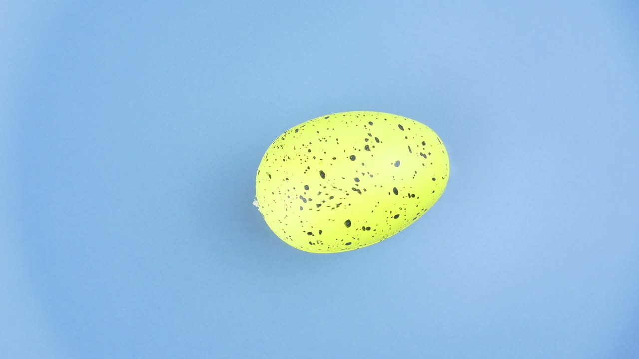 A colored Easter egg spins on a plate.