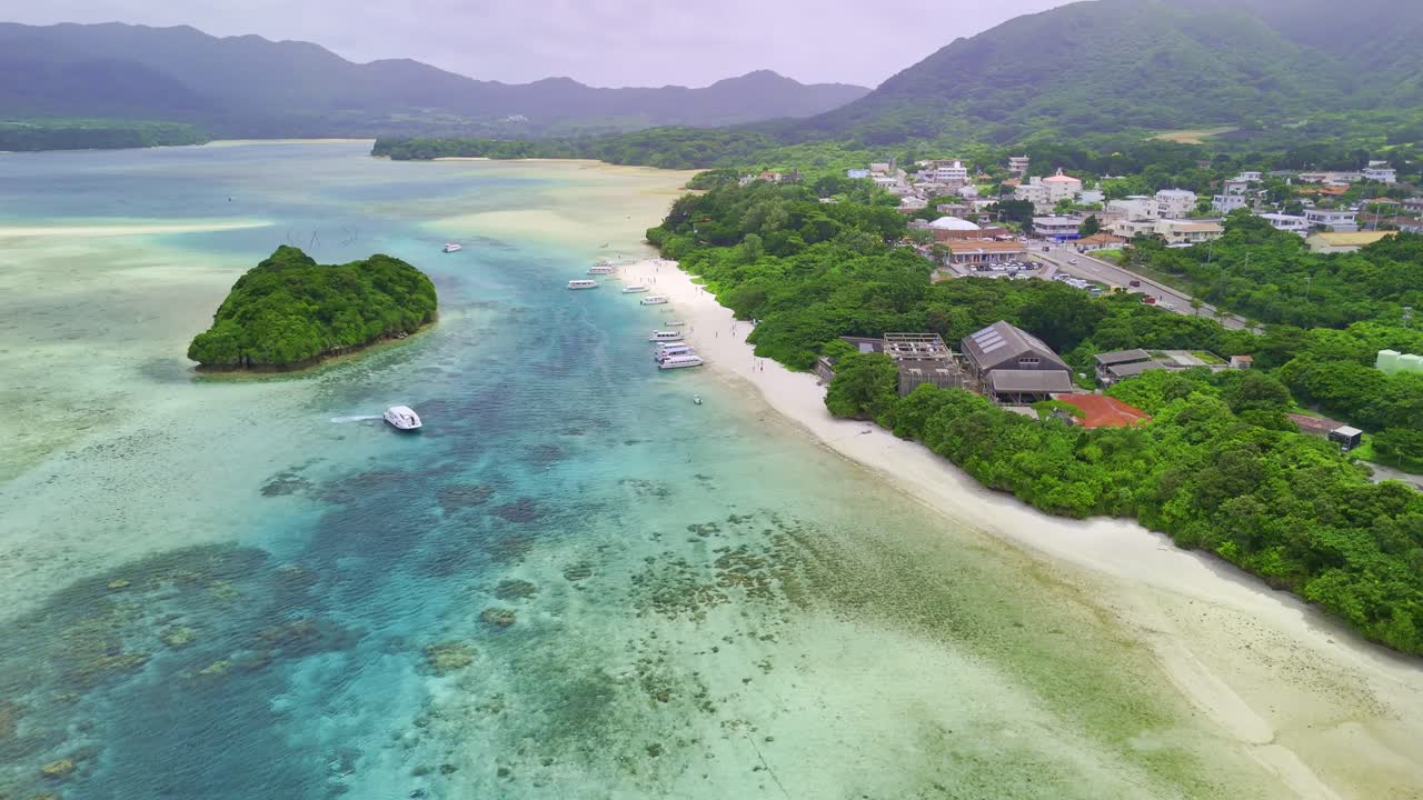 An aerial view of a boat arriving at the dock in Kabira Bay, a stunningly beautiful location with clear water, lush vegetation, and a mountainous backdrop