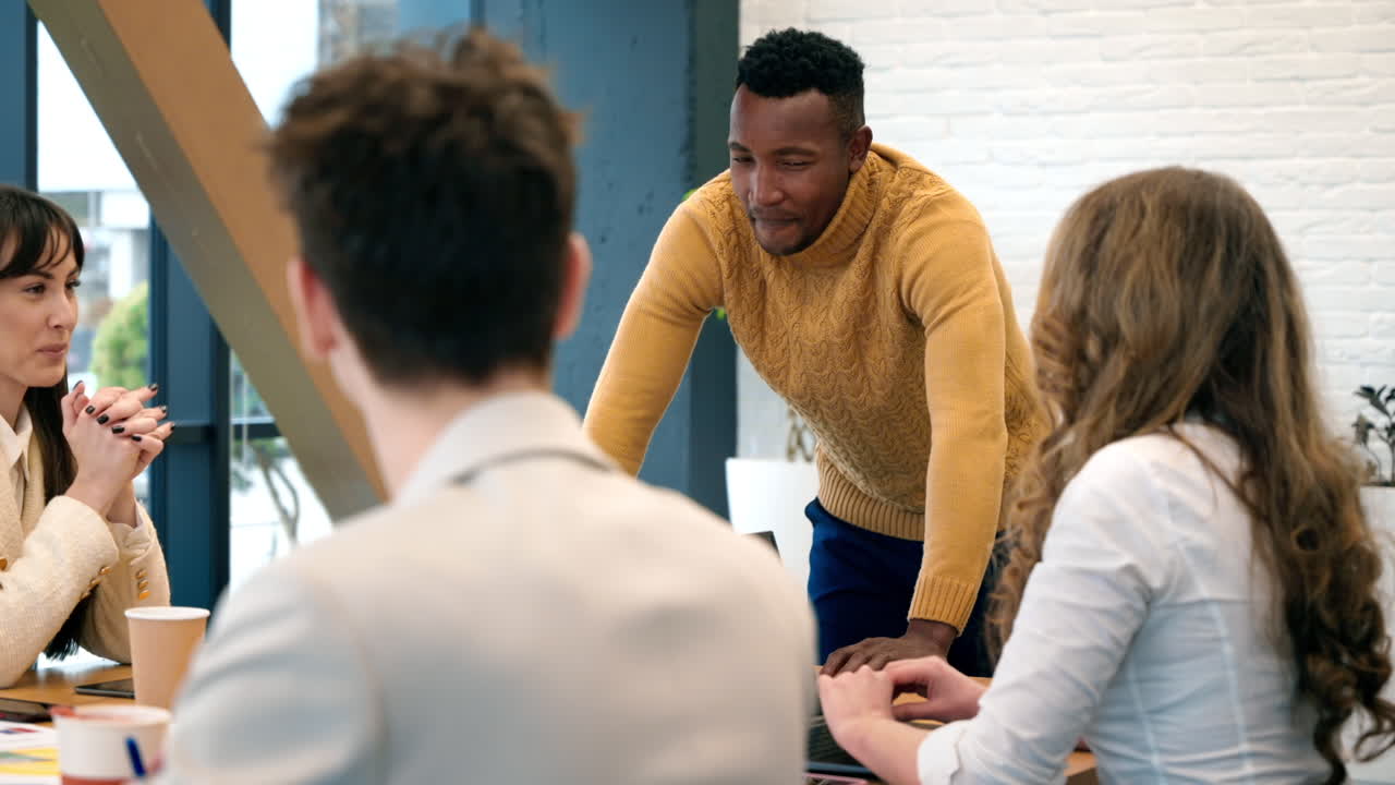 Black male team leader at business meeting in an office, discussing business affairs with other workers