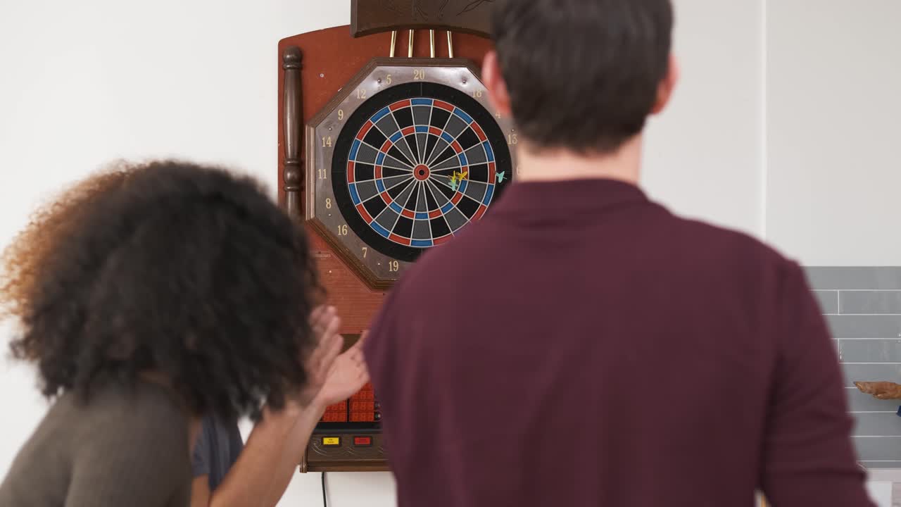 Young man playing game of dart with friends at home
